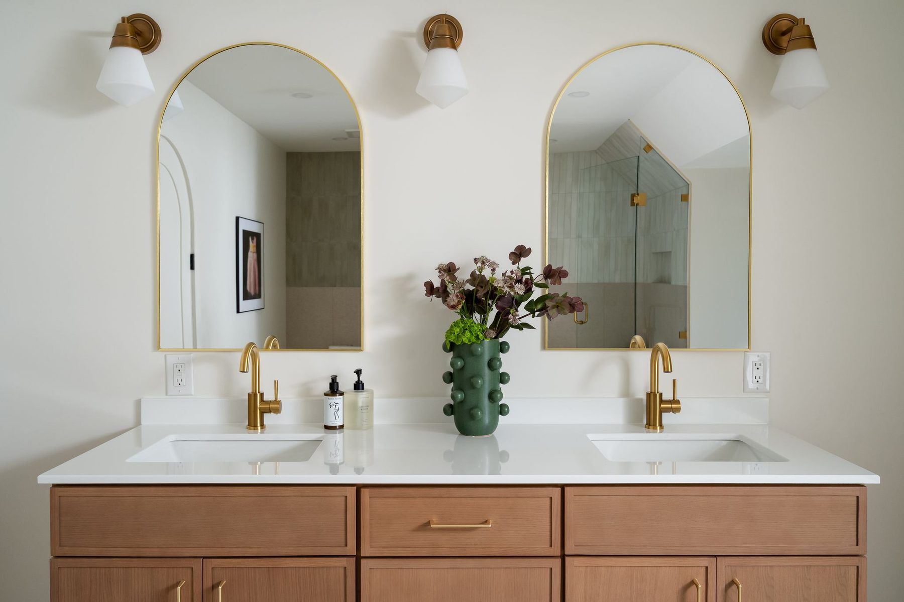 Serene primary washroom with a double vanity and arched mirrors