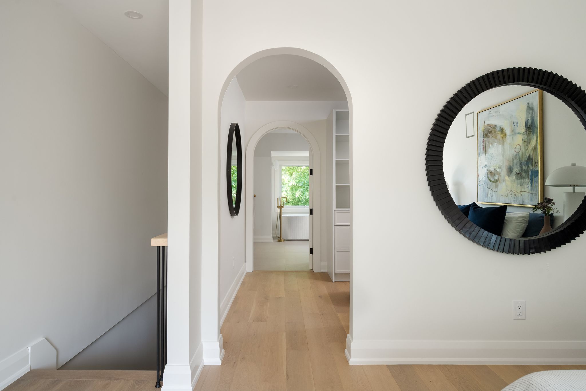A sequence of softly curved arches leading from the primary bedroom into the ensuite washroom