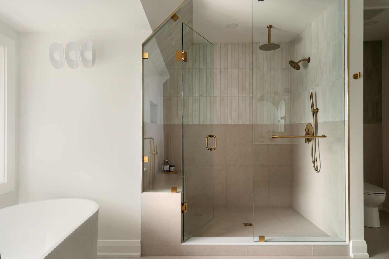 Primary washroom with a glass shower enclosure and sculptural freestanding tub